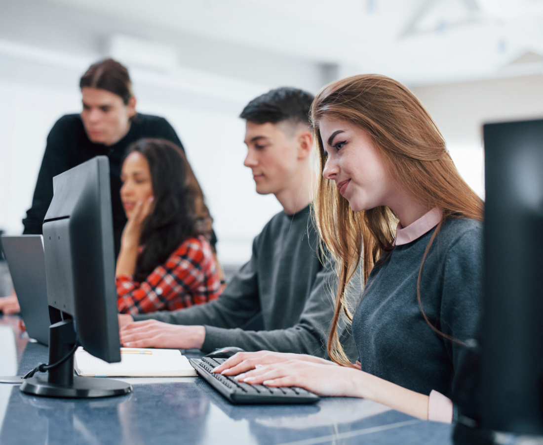 Computer screens. Group of young people in casual clothes working in the modern office.